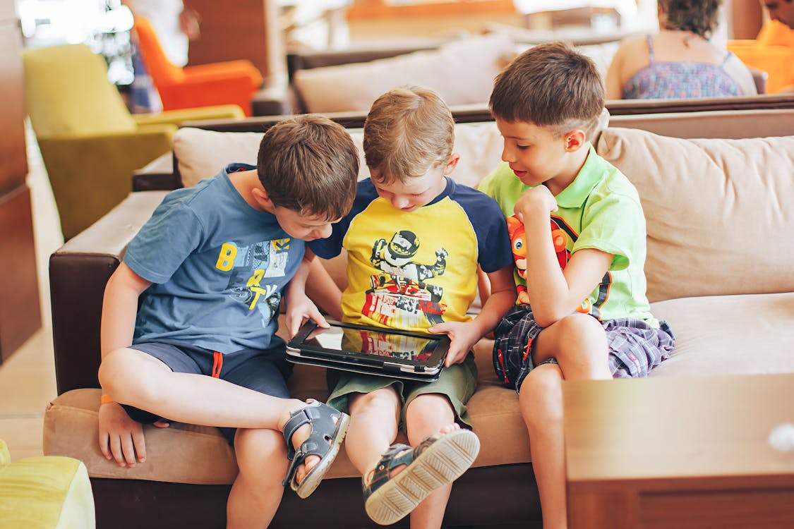 Roblox's new AI tool speeds up game environment creation, allowing modifications with simple text commands 1 Free Boys Sitting on Couch Playing on Tablet Stock Photo